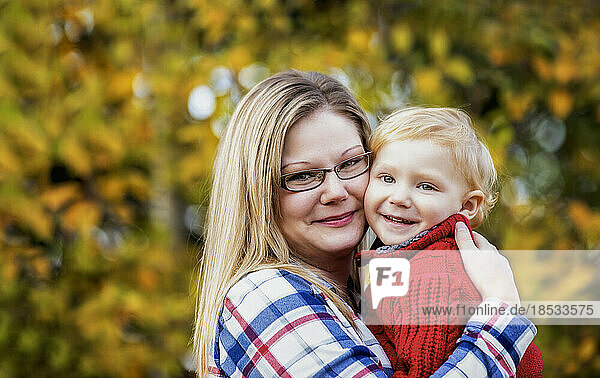 Porträt einer Mutter im Freien  die ihren kleinen Sohn im Arm hält  in einer Parkanlage im Herbst; Edmonton  Alberta  Kanada