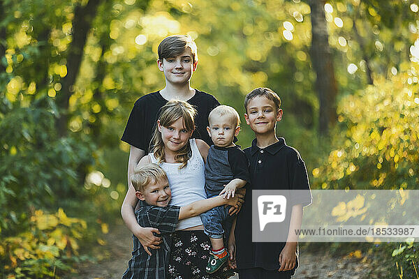 Outdoor portrait of five young siblings standing on a trail in a woodland; Edmonton  Alberta  Canada
