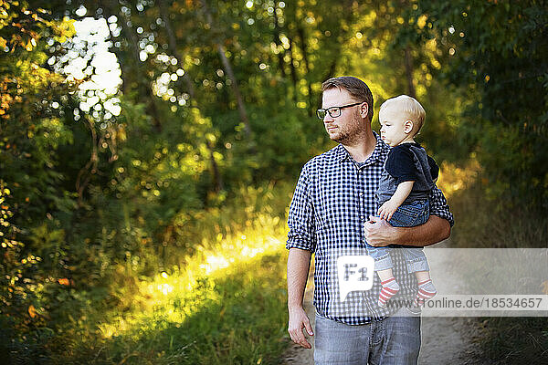Father walks with his baby boy outdoors in a park; Edmonton  Alberta  Canada