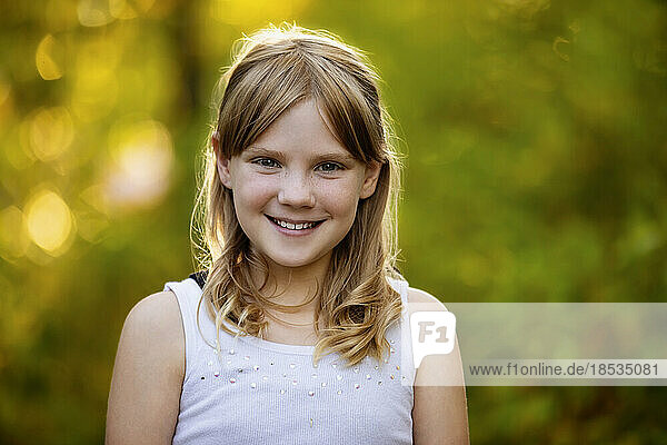 Close-up outdoor portrait of a sweet young girl with blond hair with autumn colours in the background; Edmonton  Alberta  Canada