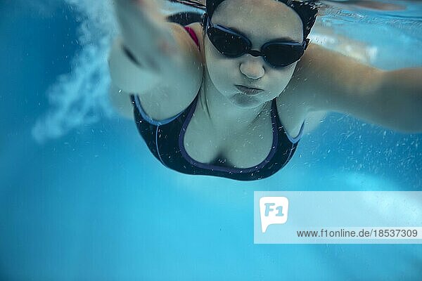 Junge Frau auf Schwimmen Hintergrund. Weiblich gekleidet in Badebekleidung  schwimmen in Sportverein und Durchführung von Wasser Aktivitäten