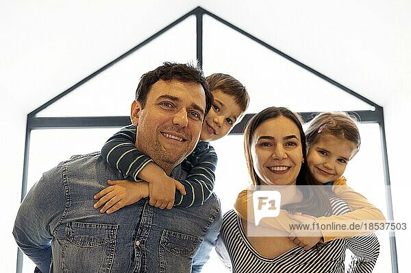 Glückliche Eltern mit Sohn und Tochter posieren in Innenräumen. Schöne Familie Blick in die Kamera in der modernen Wohnung zu Hause  glückliche Elternschaft Familienkonzept