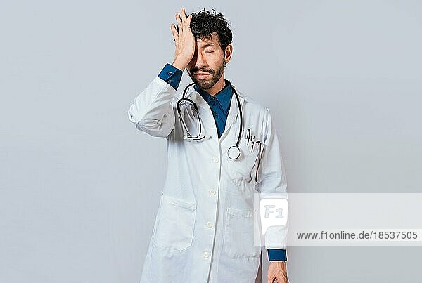 Tired doctor with hand on forehead  Exhausted doctor with hand on forehead isolated
