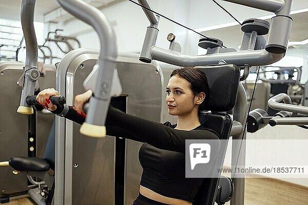 Attraktive brünette sportliche Frau macht Übungen auf dem Simulator im Fitnessclub. Sport  Gesundheitswesen  Fitnesskonzept