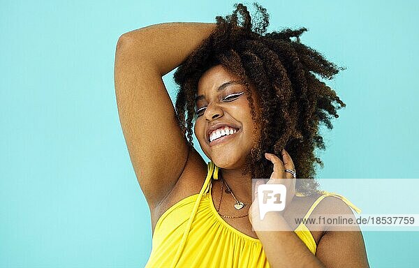 Schöne helle freudige afrikanische Frau in gelbem Kleid in blauem Studio Hintergrund