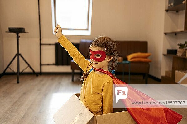 Superhelden Kind. Superheldenkind  das zu Hause in einer Kiste spielt. Bewegung  Erfolg und freudiges Spielkonzept