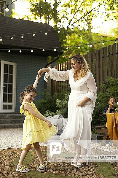 Mutter und kleine Tochter haben Spaß im Freien. Hochzeit  schöne Braut mit einem kleinen Mädchen tanzen zusammen. Liebe  Familie  Feier