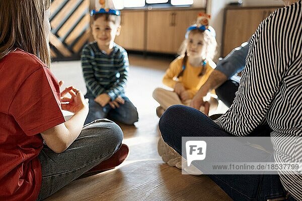 Glückliche junge Familie mit Kindern spielen ein Kartenspiel zu Hause auf dem Boden sitzen. Mutter  Vater  Sohn und Töchter spielen Kartenspiele in einem Wohnzimmer