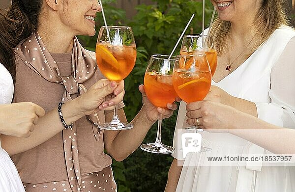 Glückliche Freunde verbringen Zeit miteinander  Fokus auf junge Frauen  die Aperol Spritz Cocktail trinken. Sommer Hochzeitsfeier. Fröhlichkeit und Feier Konzept