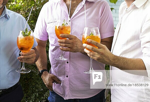 Männliche Freunde verbringen Zeit miteinander und trinken einen Aperol Spritz Cocktail auf einer Sommerparty. Zusammen reden
