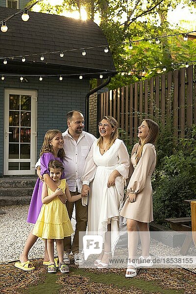 Glückliche Eltern mit Kindern  Feier im Garten. Foto von Familie auf einer Hochzeitsparty für ein 20 jähriges Jubiläum im Hinterhof Partei