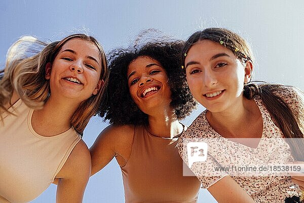 Eine Gruppe von Teenagern verschiedener Nationalitäten und unterschiedlichen Aussehens hat Spaß zusammen. Junge und positive Studentinnen in Freizeitkleidung mit Rucksäcken lachen und unterhalten sich auf der Straße Freundschaft Konzept