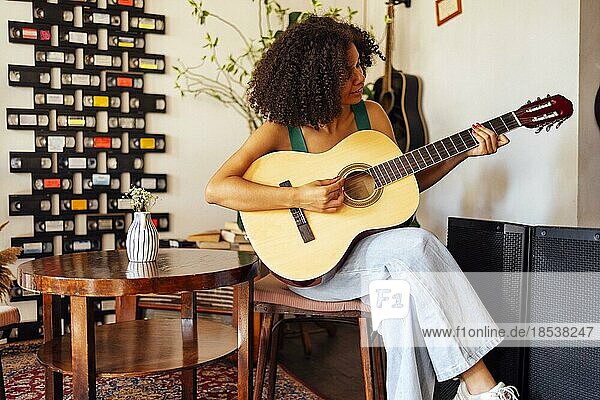 Lächelnde afroamerikanische junge Frau spielt akustische Gitarre. Mädchen spielt die Gitarre