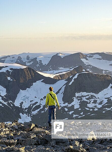 Wanderer am Gipfel des Skåla  hinten Berggipfel mit Gletscher Jostedalsbreen  bei Sonnenuntergang  Loen  Norwegen  Europa