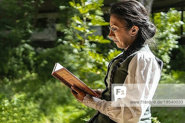Profilbild einer lateinamerikanischen Frau in traditioneller Kleidung  die in einem Park sitzend ein Buch liest