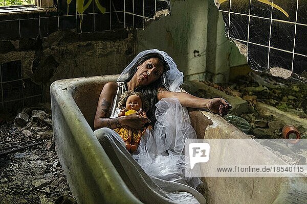 Verwirrte Braut mit einer Puppe in einer Badewanne. Inspiriert von der traditionellen amerikanischen Legende von la llorona (der weinenden Frau)
