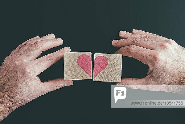 Hände  die Holzklötze mit rotem Herz  Liebe oder gebrochenem Herz verbinden oder trennen