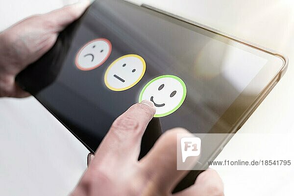 Zufriedene Person  die ein positives Feedback gibt  indem sie ein Smiley-Gesicht auf dem Touchscreen eines digitalen Tablets berührt  Konzept zur Bewertung der Dienstleistungsqualität