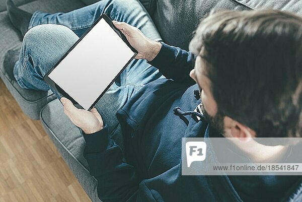 high angle view of man relaxing on couch while using tablet computer