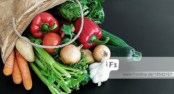 Nahaufnahme von frischem Bio-Gemüse  das auf dem Wochenmarkt in einer braunen Papiertüte gekauft wurde  vor einem dunklen Tischhintergrund