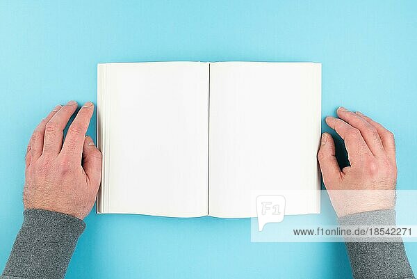 Blick von oben auf eine Person  die ein Buch liest und die Hände auf beide Seiten legt  leere Seite eines gebundenen Buches mit Kopierbereich