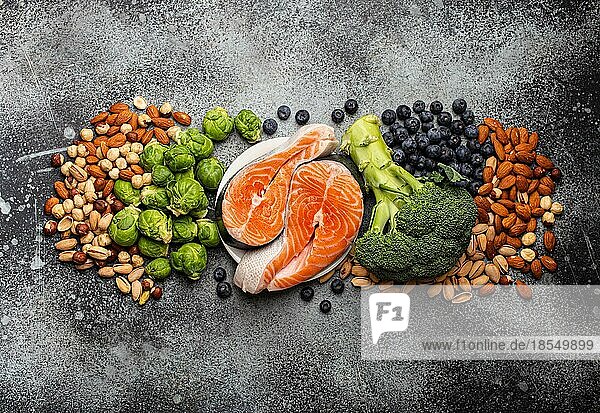 Verschiedene Lebensmittel für die Gesundheit des Gehirns und ein gutes Gedächtnis: frischer Lachs  Gemüse  Nüsse  Beeren auf einem steinernen Hintergrund. Gesunde frische Produkte zur Förderung der Gehirnleistung  Draufsicht