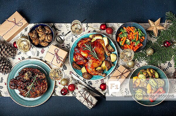 Weihnachtsabend Tischansicht mit festlichen Speisen und Sektgläsern  Weihnachtsessen mit verschiedenen leckeren Speisen  eingepackten Geschenken und Tannenbaum flach gelegt