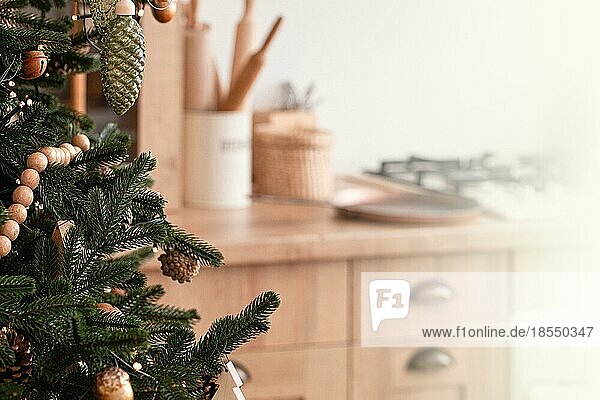 Nahaufnahme von dekoriert mit Holzspielzeug und Girlande großen schönen Weihnachtsbaum auf hellen Licht festliche moderne Küche mit Herd im skandinavischen Stil  Platz für Text