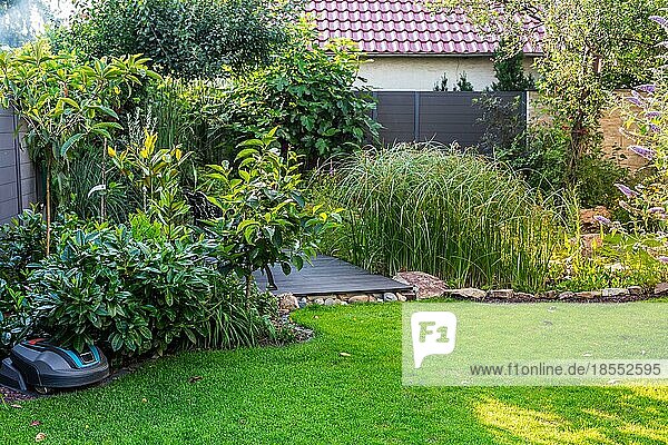 Landschaftsansicht eines schönen Gartens mit frisch gemähtem Rasen und Mähroboter in Ladestation