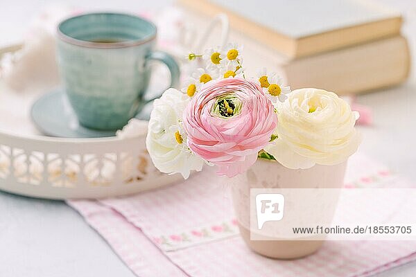 Schöne zarte Blüte von frischen Schnitt Blumenstrauß mit Tasse Tee nad Bücher im Hintergrund auf dem Küchentisch