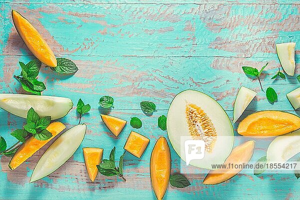 Gesunder Snack Piel de sapo Melone und Cantaloupe mit frischer Minze auf dem Zyan Holztisch