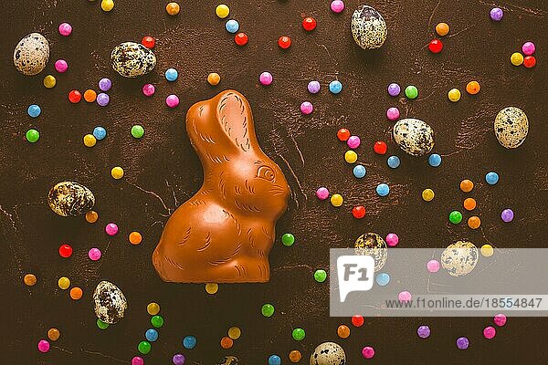 Leckere Schokoladenostereier Häschen und Süßigkeiten auf dunkelbraunem Hintergrund