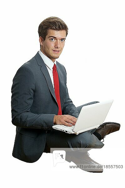 Junger Geschäftsmann mit Laptop auf den Knien