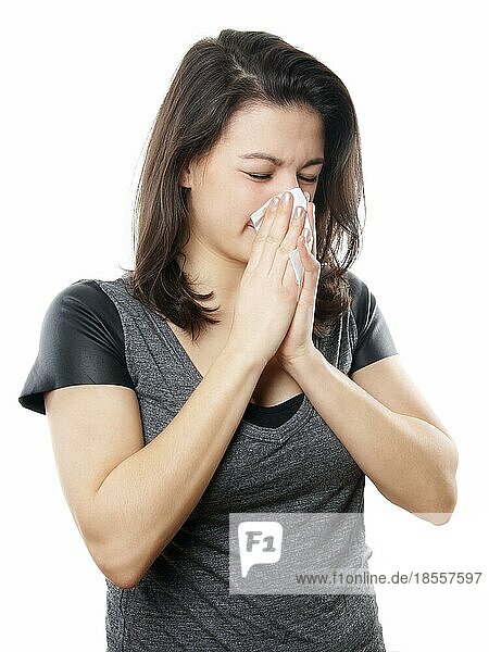 Junge Frau putzt sich die Nase mit einem Papiertaschentuch