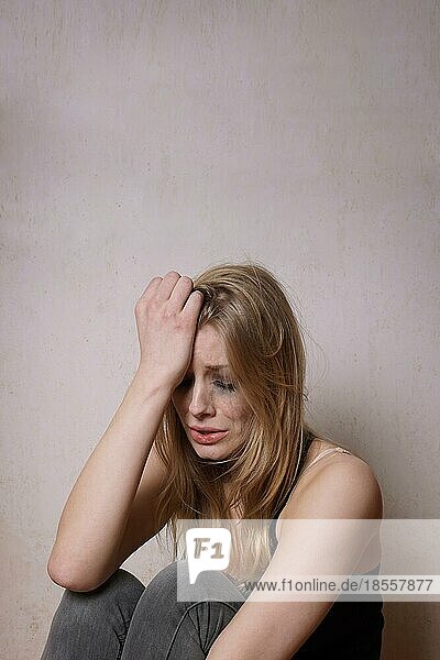 Traurige junge Frau mit tränenverschmiertem Gesicht und verschmiertem Make-up vom Weinen