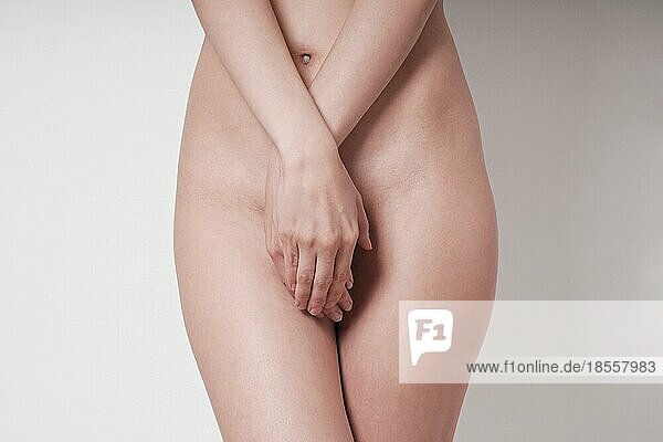 midsection of unrecognizable naked woman covering her private parts or genital area with hands