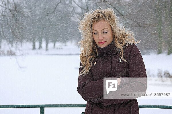 Frierende Frau bei starkem Schneefall leidet unter Winterdepression