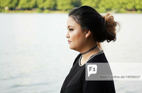 Profil oder Seitenansicht einer jungen asiatischen Frau  die am Seeufer steht
