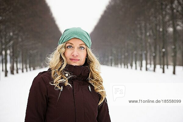 woman wearing warm winter clothing in snow covered alley with copy space