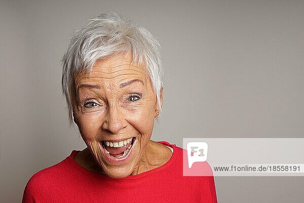 Glückliche reife ältere Frau mit kurzen weißen Haaren lachend