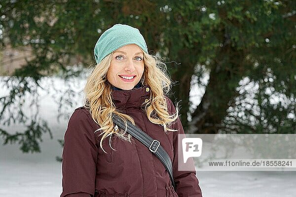 blond woman wearing warm winter fashion and woolen hat enjoying winter