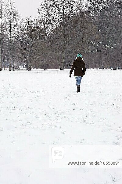 rear view of woman walking across snow covered field in winter. with copy space