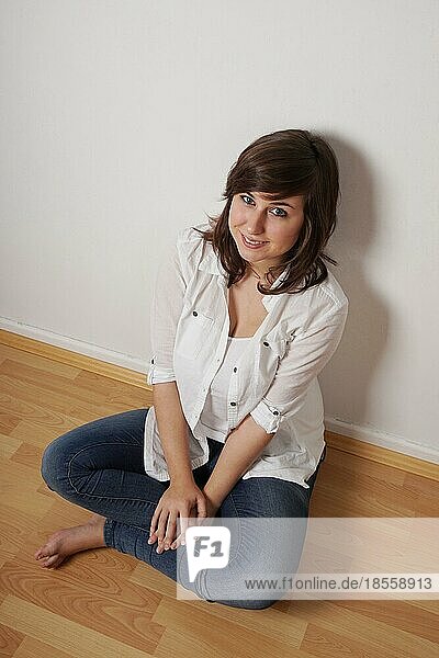 smiling young woman sitting cross-legged on floor