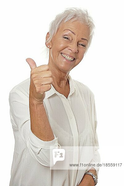 happy smiling mature woman in her sixties with trendy white short hair making thumbs up hand sign