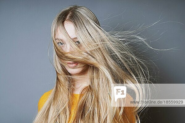 Blonde junge Frau mit langem  vom Wind zerzaustem Haar  das ihr ins Gesicht weht