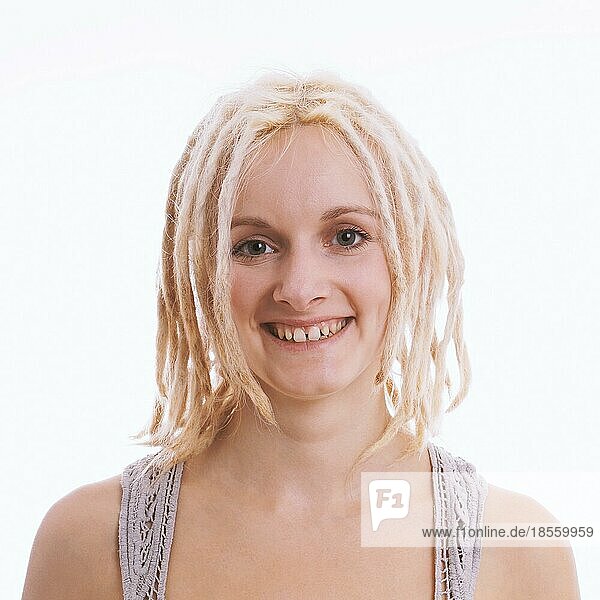 happy smiling young woman with blond dreadlocks and tooth gap - studio headshot against white background