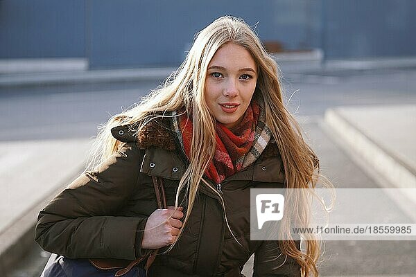 candid street style portrait of teenage girl waiting at bus stop on a sunny day in winter
