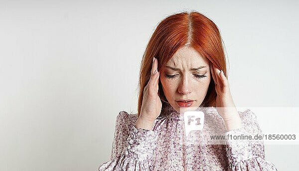 Mittlere erwachsene Frau mit stressbedingten Kopfschmerzen oder Migräne  die sich mit geschlossenen Augen die Schläfen reibt