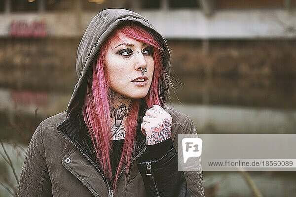 portrait of thoughtful young woman with piercings and tattoos
