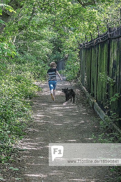 Rear view of boy with dog running on footpath